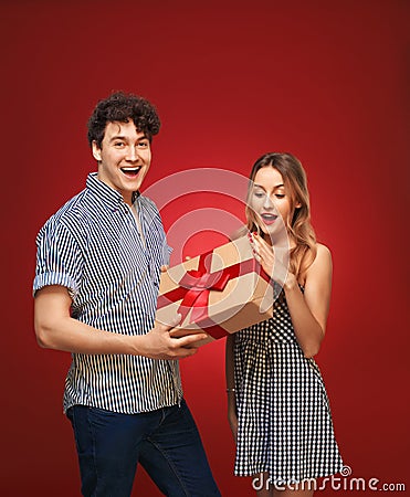 Boy gives a girl a gift in a pin up style, on a red bac Stock Photo