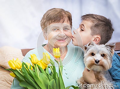 Boy giving a bunch of flowers to grandmother. Grandson and grandma spending, enjoying time together. Stock Photo
