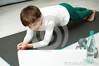 The boy goes in for sports at home online. The child does exercises in the room Stock Photo