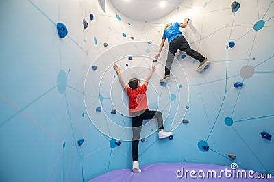 Boy hanging on wall lending helping hand to friend Stock Photo