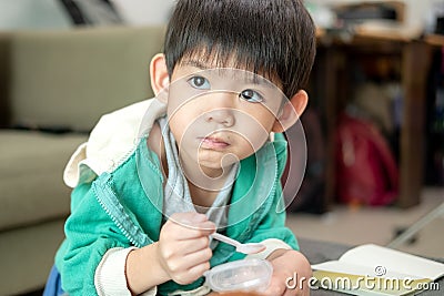 A boy happily uses a spoon to scoop up yogurt Stock Photo