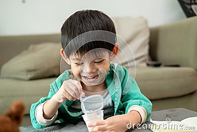 A boy happily uses a spoon to scoop up yogurt Stock Photo