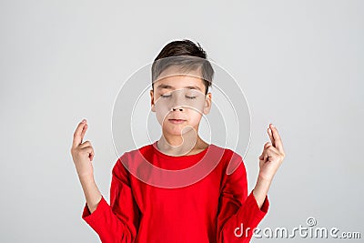 The boy has closed eyes and has crossed fingers on good luck or Stock Photo
