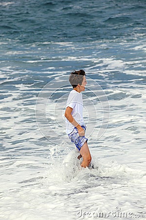 Boy has fun in the spume at the black beach Stock Photo