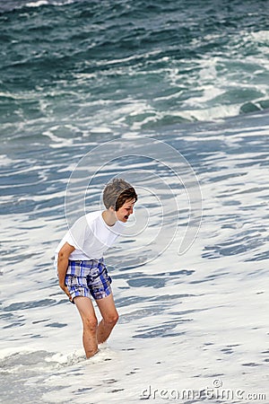 Boy has fun in the spume at the black beach Stock Photo