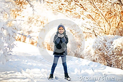 Boy in hat and scarf stands near the tree with snow and has some snoflakes in his hands. Christmas New Year mood. Winter time. Sno Stock Photo