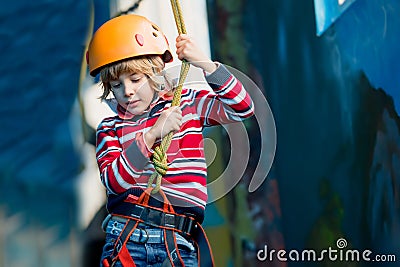 Boy having fun and playing at adventure park, holding ropes and climbing wooden stairs Stock Photo