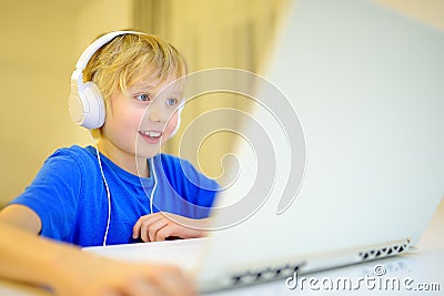 A boy in headphones plays a computer game or chats with a friend in a messenger. Child and gadgets. Little kids using modern Stock Photo