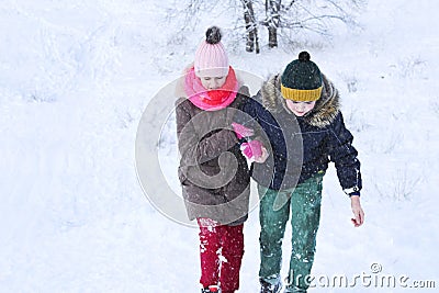 The boy helps the girl to climb out of the snow and move on Stock Photo