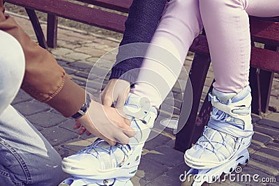 Boy helps the girl to wear roller skates. Stock Photo