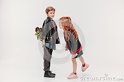 boy hiding roses for his little girlfriend behind back Stock Photo