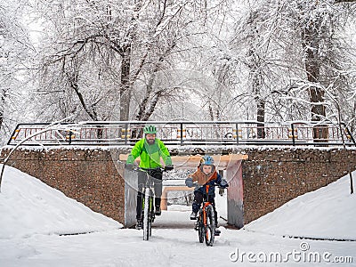 A boy and his father ride bicycles in a winter park Stock Photo