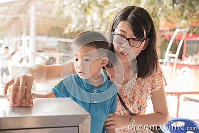 Boy and his mother all toghter donate by put money in donation box. Stock Photo