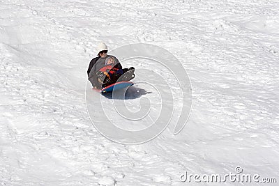 Boy and his mother sledding Stock Photo