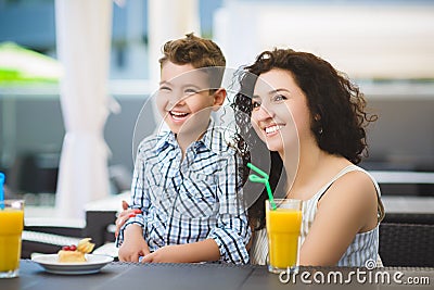 Boy and his mother tasting dessert with juice in resort restaurant outdoor Stock Photo