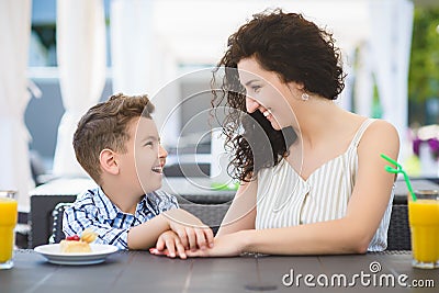 Boy and his mother tasting dessert with juice in resort restaurant outdoor Stock Photo