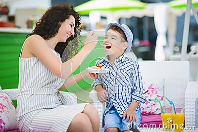 Boy and his mother tasting dessert with juice in resort restaurant outdoor Stock Photo