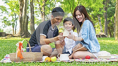 Boy hold money saving house box with mother and father in park.Happy family picnic concept. Stock Photo