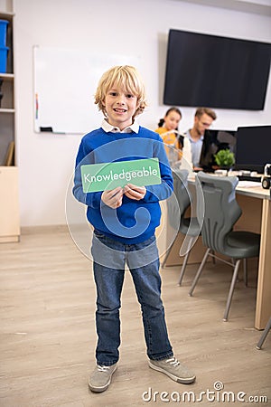 Boy holding green sign with word knowledgeable Stock Photo