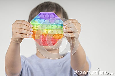 Boy holding sensory pop it fidget toy in his hands. Push pop-it fidgeting game helps relieve stress, anxiety Stock Photo