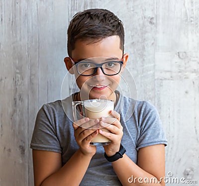 A boy holds in his hands a glass with fermented baked milk. Stock Photo