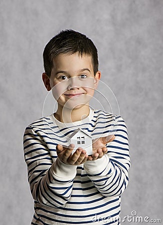 The boy holds in his hands the little white house. The concept of real estate, purchase, adoption. Stock Photo