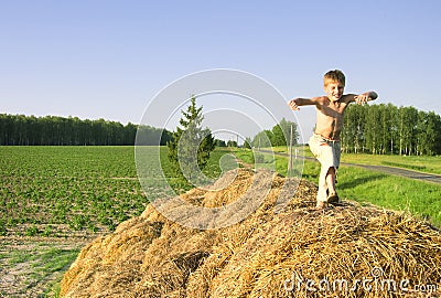 Boy jump on a hayrick and throw a straw Stock Photo