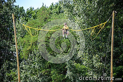 The boy is jumping on a bungee trampoline. A child with insurance and stretchable rubber bands hangs against the sky. The concept Stock Photo