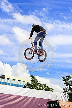 Boy jumping a high stun on a mountain bike. Young rider at the wheel of his bmx makes a trick. Biker rides on show. Extreme sport. Stock Photo