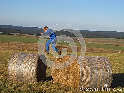Boy jumping on the straw bales Stock Photo