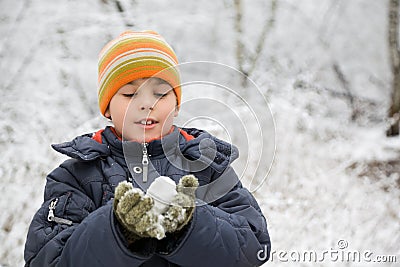 Boy keeps in hands snowball in wood in winter Stock Photo