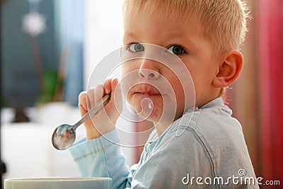 Boy kid child eating corn flakes breakfast morning meal at home. Stock Photo