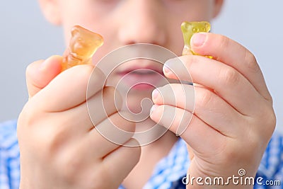 Boy, kid holding sweets in his hands, gummy bear, concept of children`s delicacy, healthy and unhealthy food, halal food Editorial Stock Photo