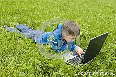 Boy with laptop computer on meadow. Stock Photo