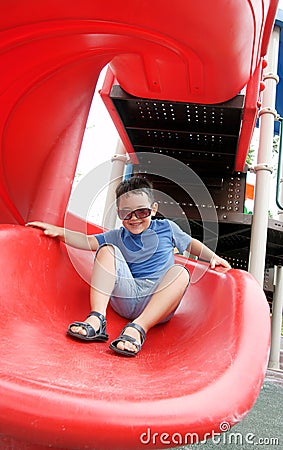 Boy laughing and sliding down on a spiral slide Stock Photo