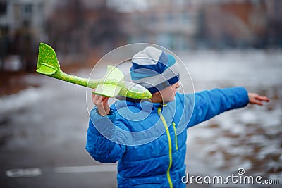 The boy launches a glider plane green in winter. Active games on the air. Airplane flights. Traveling in the winter Stock Photo
