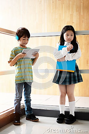 Boy is listening music from headphone,girl is holding books in hand Stock Photo