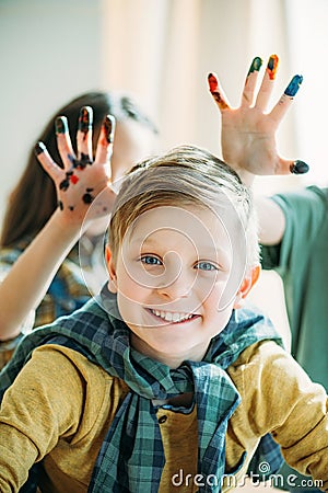 Boy looking at camera, girls with painted hands behind. kids drawing school concept Stock Photo