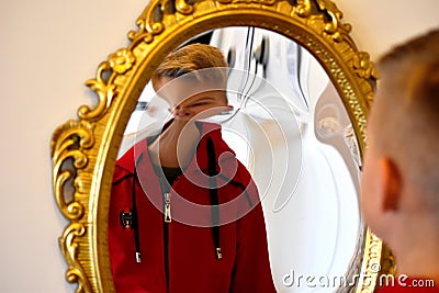 The child reflected in a distorting mirror. A fun reflection of the boy. Children`s entertainment Stock Photo