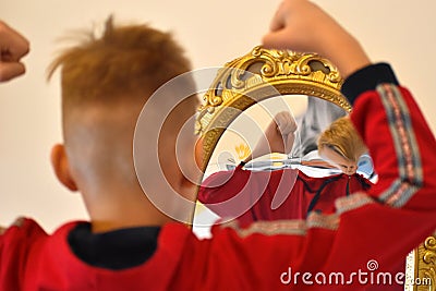 The child reflected in a distorting mirror. A fun reflection of the boy. Children`s entertainment Stock Photo