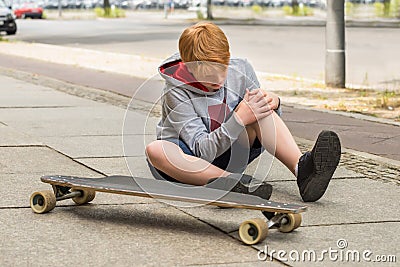 Boy Looking At His Injured Leg Stock Photo