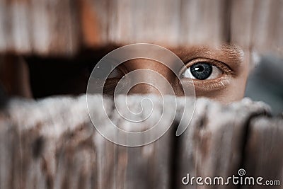 Boy looks through the gap in the fence. The concept of voyeurism, curiosity, Stalker, surveillance and security Stock Photo