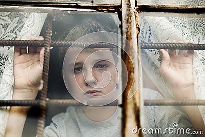 The boy looks out of the window through a lattice Stock Photo