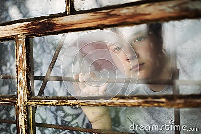 The boy looks out of the window through a lattice Stock Photo