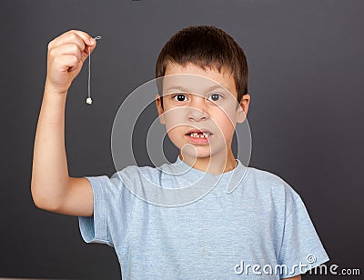 Boy with lost tooth on thread Stock Photo