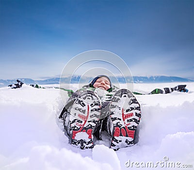 Boy lying in deep snow on the mountain hill Stock Photo