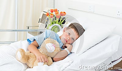 Boy lying with teddy bear in hospital Stock Photo