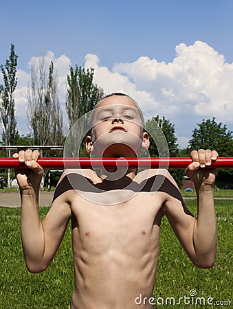 Boy makes sport exercises on the horizontal bar Stock Photo