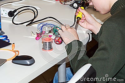 A boy making a robot with the electric soldering iron Editorial Stock Photo