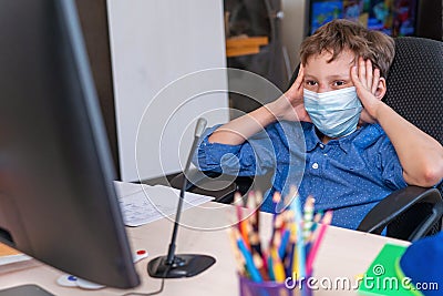 Boy with mask on his face is tired distance learning during quarantine covid-19 Stock Photo